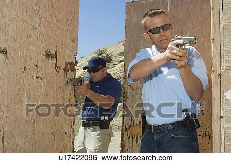 Two men aiming hand guns at firing range View Large Photo Image Stock Photograph - Two men aiming hand guns at firing range. Fotosearch