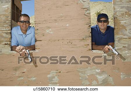 Two men holding hand guns at firing range, portrait View Large Photo Image Stock Image - Two men holding hand guns at firing range, portrait. Fotosearch