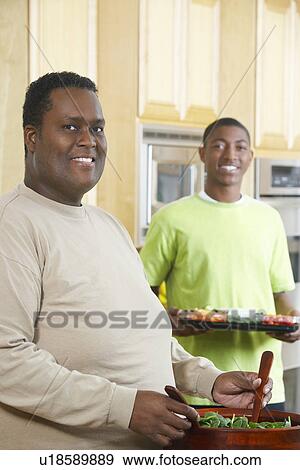 Stock Photo - Two men making salad in kitchen. Fotosearch