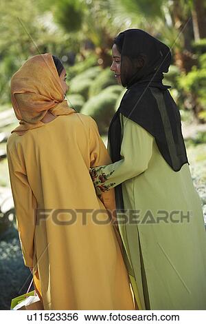 Stock Photograph - Two muslim woman in traditional clothing, back view. Fotosearch