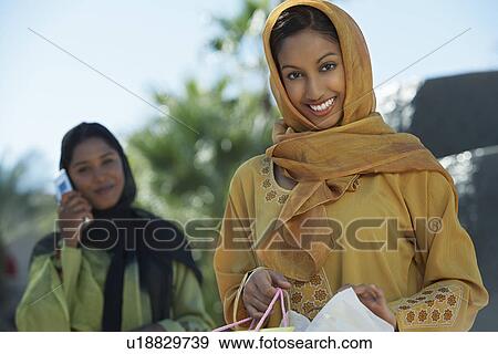 Stock Photo - Two muslim woman, one with shopping bag. Fotosearch