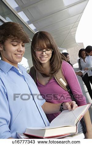 Stock Image - Two students reading book at school. Fotosearch