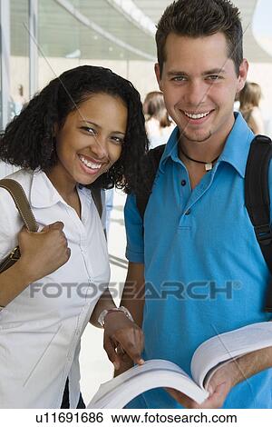 Stock Photograph - Two students smiling in school, portrait. Fotosearch
