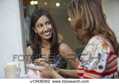 Stock Image - Two women chatting at cafe table. Fotosearch