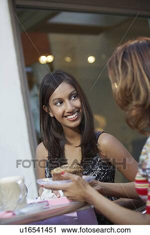 Stock Image - Two women chatting at cafe table. Fotosearch