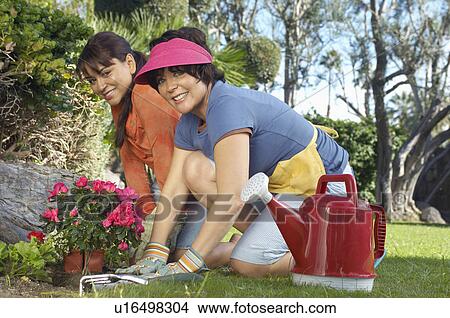 Picture - Two women planting flowers in garden. Fotosearch