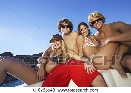 Stock Image - Two young couples relaxing on boat at lake, portrait. Fotosearch