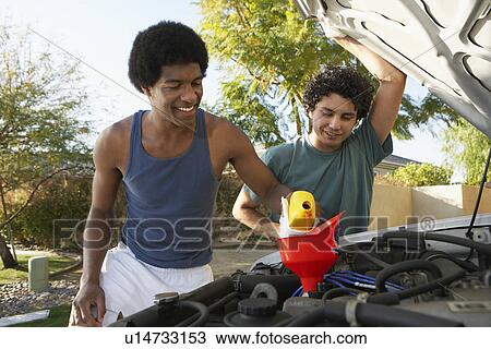 Two young men pouring oil into car engine View Large Photo Image Stock Image - Two young men pouring oil into car engine. Fotosearch