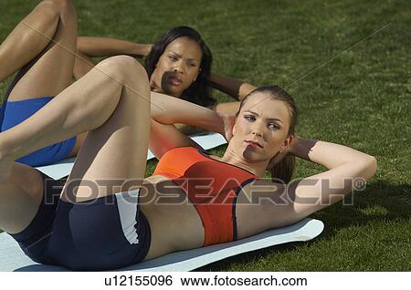 Stock Photograph - Two young women exercising in park. Fotosearch