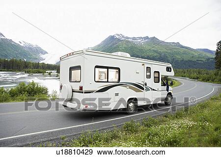 Stock Photo - USA, Alaska, recreational vehicle driving on road, side view. Fotosearch