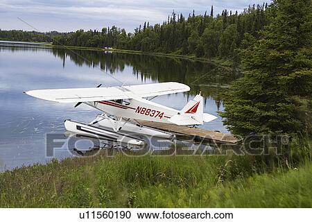 Stock Image - USA, Alaska, sea plane tied to pier on lake, elevated view. Fotosearch