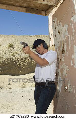 Woman aiming hand gun at firing range View Large Photo Image Stock Image - Woman aiming hand gun at firing range. Fotosearch