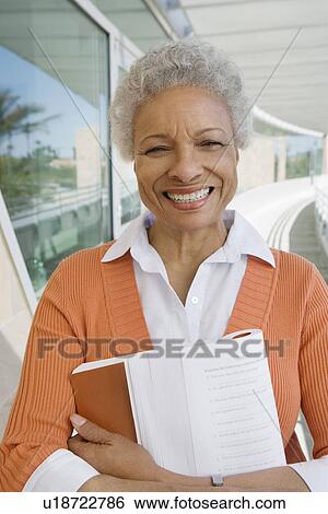Stock Photograph - Woman embracing book at school, portrait. Fotosearch