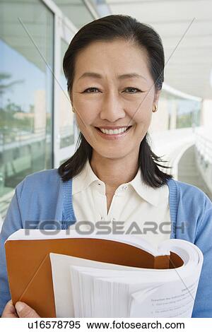 Woman embracing book at school, smiling, portrait View Large Photo Image Stock Photography - Woman embracing book at school, smiling, portrait. Fotosearch