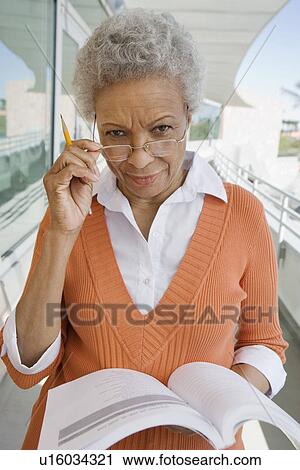 Stock Image - Woman holding book at school, portrait. Fotosearch