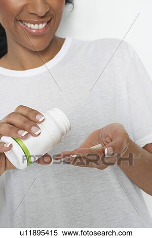 Stock Photography - Woman holding bottle of pills, close-up. Fotosearch