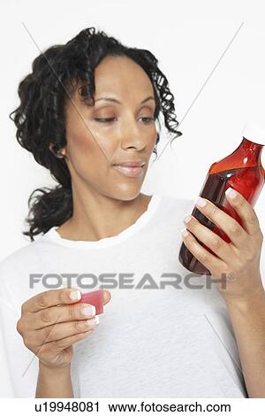Woman holding medicine, reading bottle, studio shot View Large Photo Image Stock Image - Woman holding medicine, reading bottle, studio shot. Fotosearch