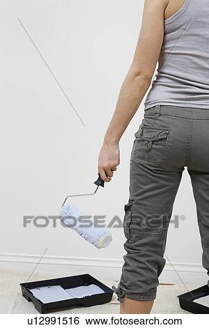 Woman holding paint roller by blank wall, mid section View Large Photo Image Stock Photograph - Woman holding paint roller by blank wall, mid section. Fotosearch