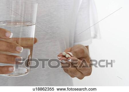 Woman holding pills and glass of water, mid section View Large Photo Image Stock Photography - Woman holding pills and glass of water, mid section. Fotosearch