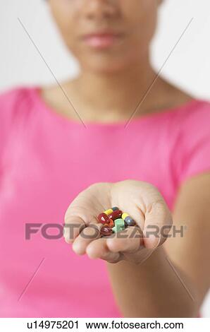 Stock Image - Woman holding pills, focus on hand. Fotosearch