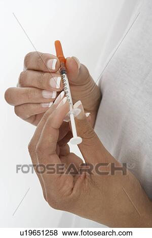 Stock Photo - Woman holding syringe, close-up of hands. Fotosearch