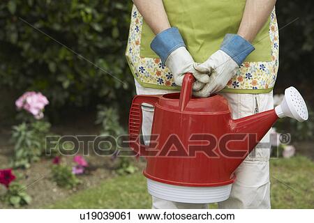 Woman holding watering can in garden, mid section View Large Photo Image Stock Image - Woman holding watering can in garden, mid section. Fotosearch
