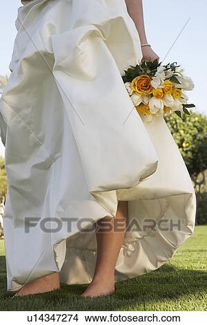 Woman in elegant dress standing barefoot in grass, low section View Large Photo Image Picture - Woman in elegant dress standing barefoot in grass, low section. Fotosearch