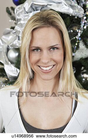 Stock Photograph - Woman in front of Christmas tree, portrait. Fotosearch