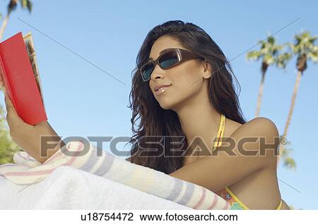 Stock Image - Woman reading book outdoors. Fotosearch