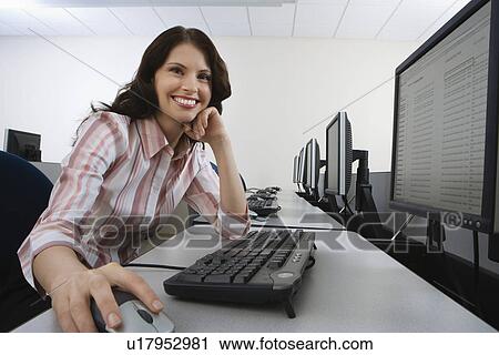 Woman sitting at desk in front of computer View Large Photo Image Stock Image - Woman sitting at desk in front of computer. Fotosearch