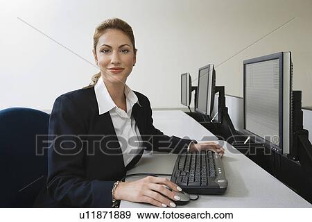 Stock Photo - Woman sitting at row of computers, portrait. Fotosearch