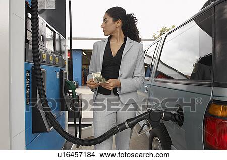 Woman standing by van with fuel pump counting money View Large Photo Image Picture - Woman standing by van with fuel pump counting money. Fotosearch