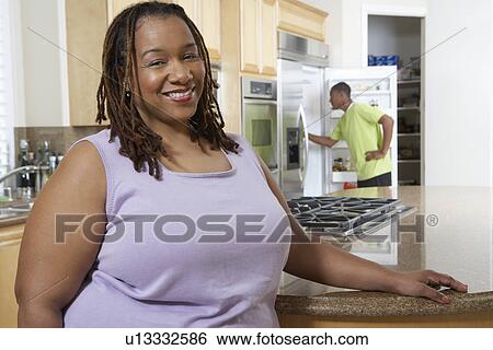 Woman standing in kitchen, smiling, portrait View Large Photo Image Stock Photograph - Woman standing in kitchen, smiling, portrait. Fotosearch