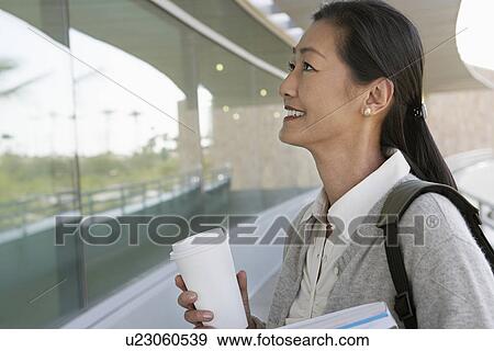 Stock Photo - Woman standing outside school, smiling. Fotosearch