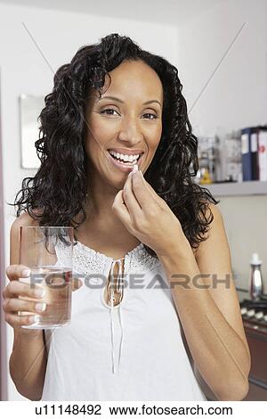 Woman taking medication, smiling, indoors, portrait View Large Photo Image Stock Image - Woman taking medication, smiling, indoors, portrait. Fotosearch