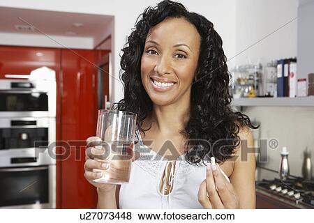 Stock Photo - Woman taking medication, smiling, indoors, portrait. Fotosearch
