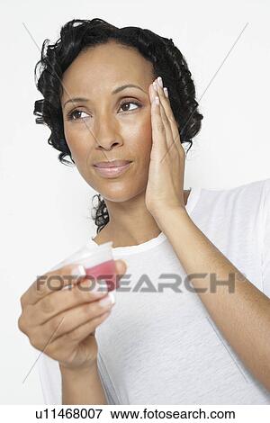 Stock Photo - Woman taking medicine, with hand on head, close-up. Fotosearch