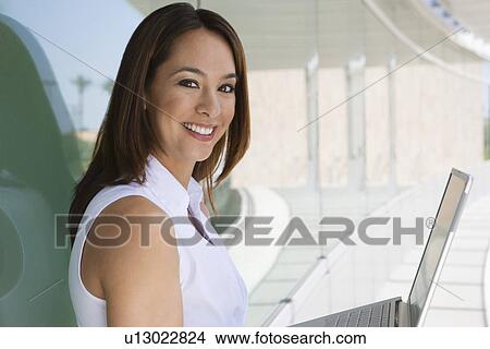 Picture - Woman using laptop outdoors, portrait. Fotosearch