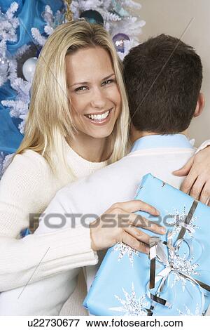 Stock Photo - Woman with Christmas present hugging man. Fotosearch