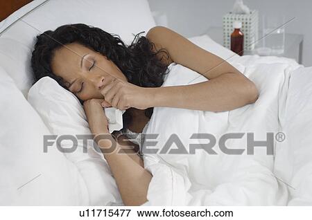 Stock Photo - Woman with flu lying in bed. Fotosearch