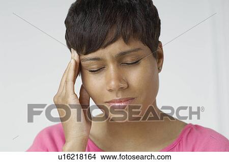 Picture - Woman with hand on forehead, indoors. Fotosearch