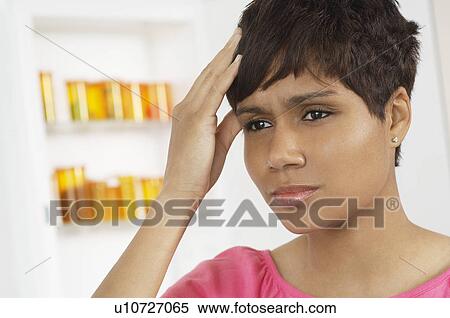 Stock Photography - Woman with hand on head, near pill cabinet. Fotosearch