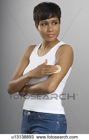 Stock Image - Woman with patch on arm, studio shot. Fotosearch