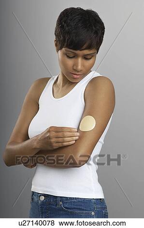 Woman with patch on arm, studio shot View Large Photo Image Stock Photo - Woman with patch on arm, studio shot. Fotosearch