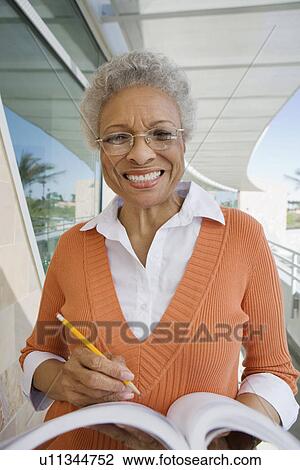 Stock Image - Woman writing in book at school, portrait. Fotosearch