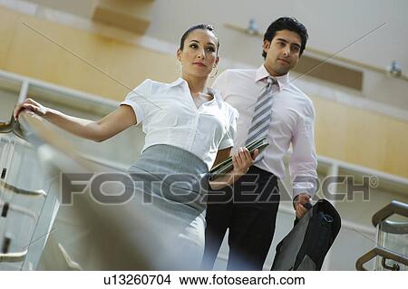 Picture - Young business woman and business man walking down stairs. Fotosearch