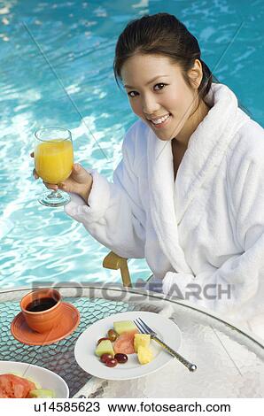 Young Chinese woman drinking orange juice by swimming pool, portrait View Large Photo Image Stock Image - Young Chinese woman drinking orange juice by swimming pool, portrait. Fotosearch