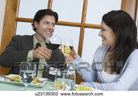 Young couple at restaurant table, toasting with wine View Large Photo Image Stock Image - Young couple at restaurant table, toasting with wine. Fotosearch