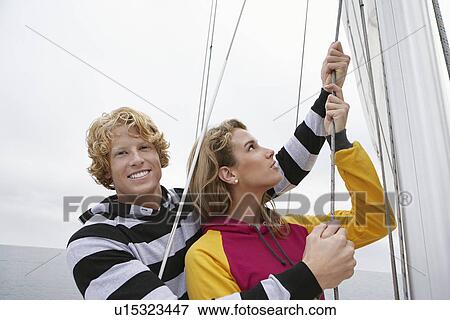Stock Photo - Young couple holding rigging on sailboat, portrait. Fotosearch
