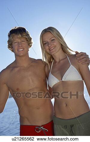 Stock Image - Young couple in swimwear outdoors, portrait. Fotosearch